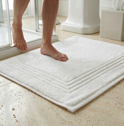 alfombra de baño blanca con relieve junto a la ducha con hombre descalzo
