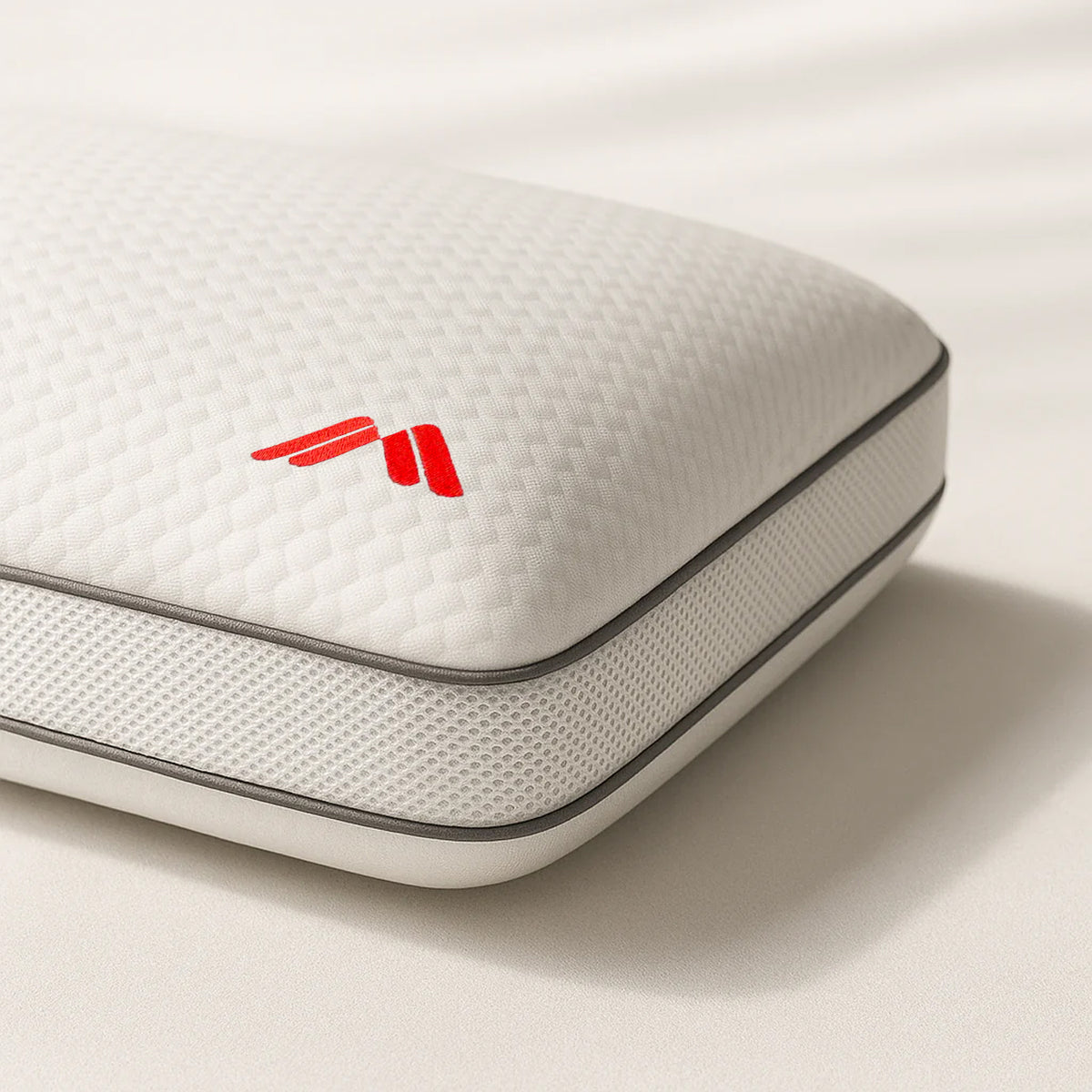 Detalle de la funda texturizada con logo rojo y ribete gris de la almohada viscoelástica AirHigh de Morfeo.