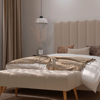 Banqueta Milos color beige de Morfeo con tapizado capitoné en ambiente de dormitorio, colocada a los pies de la cama.