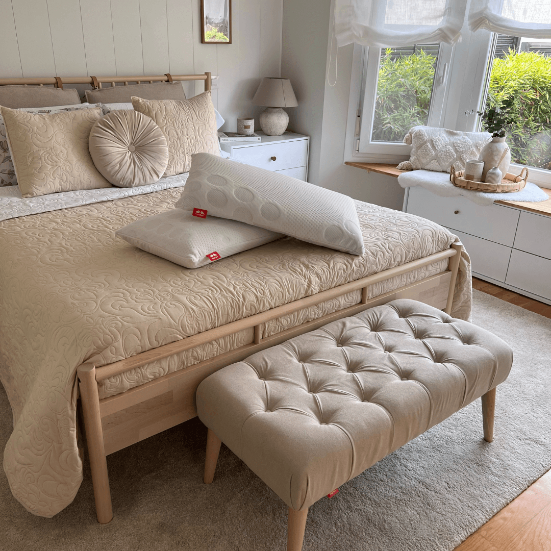 Banqueta Milos color beige de Morfeo con tapizado capitoné en ambiente de dormitorio colocada a los pies de la cama.