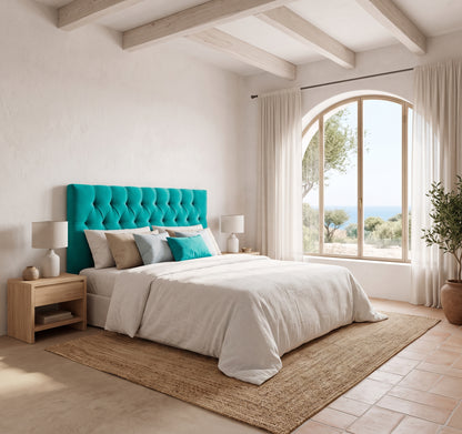Cabecero tapizado Capy turquesa capitoné de Morfeo en un dormitorio mediterráneo con arco y vistas al mar.