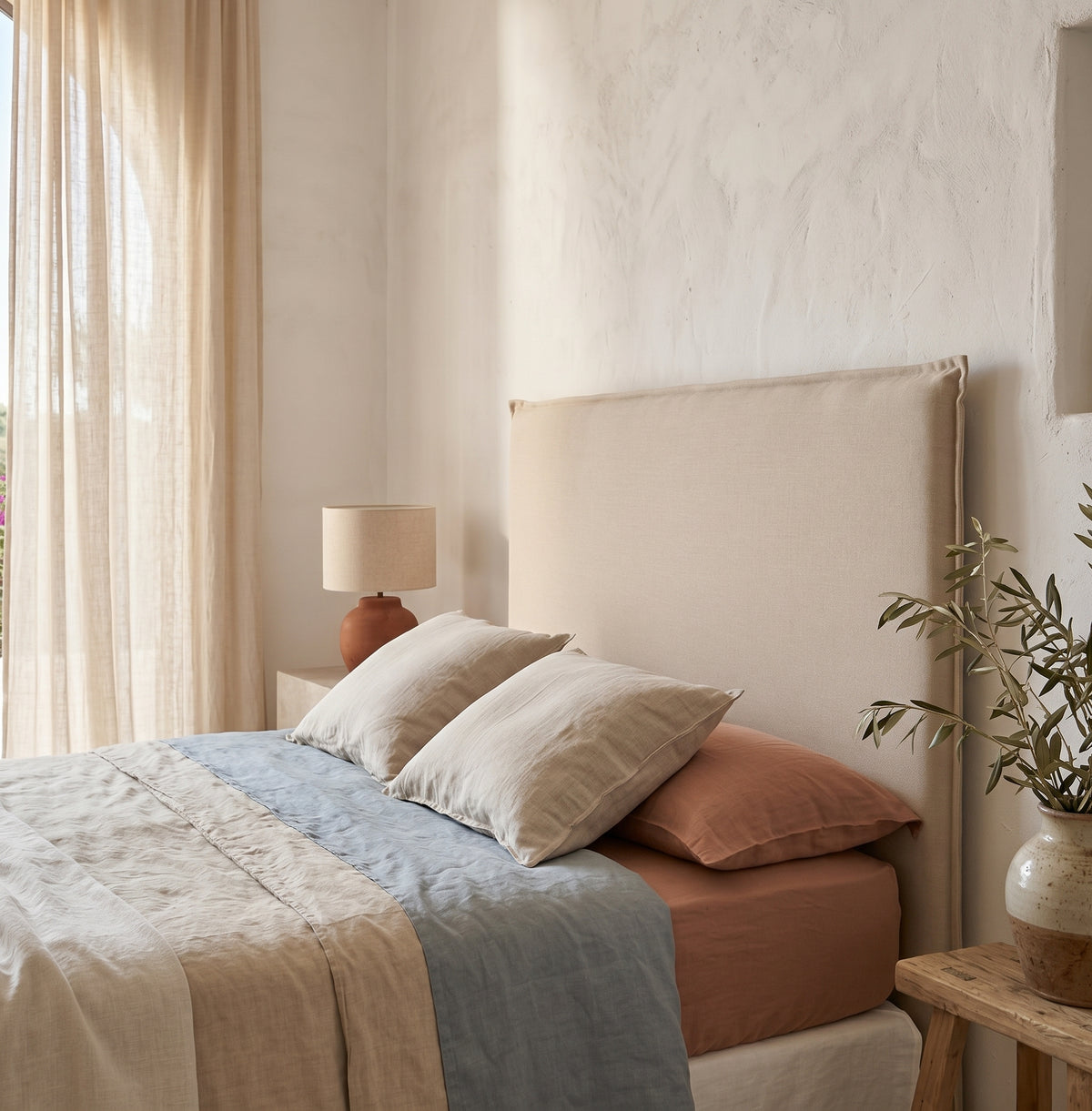 Detalle del cabecero tapizado liso Lin beige de Morfeo con costura perimetral, en un dormitorio de estilo mediterráneo.