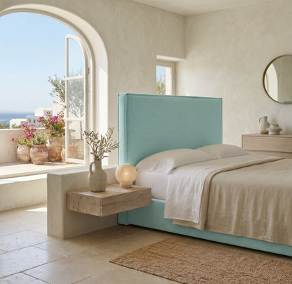 Cabecero tapizado Mox aguamarina de Morfeo, liso con vivo, en un dormitorio mediterráneo con arco y vistas al mar.