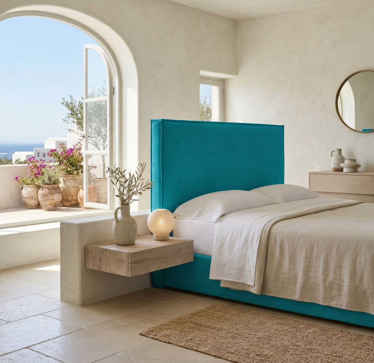 Cabecero tapizado Mox turquesa de Morfeo, liso con vivo, en un dormitorio mediterráneo con arco y vistas al mar.
