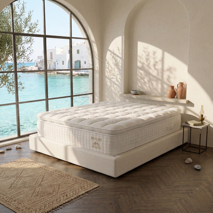 Colchón Aurum de Morfeo en una habitación mediterránea con ventanal en arco y vistas al mar.