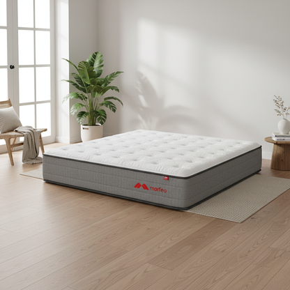 Colchón Morfeo XL sobre alfombra en una habitación luminosa con suelo de madera y plantas.