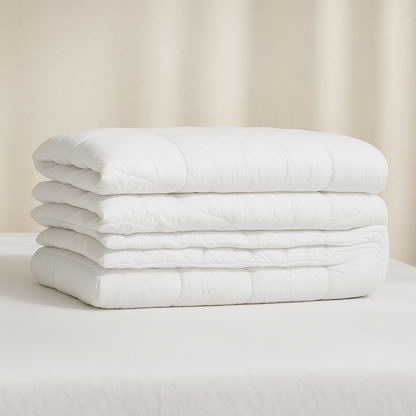Edredón nórdico ECO de Morfeo doblado en varias capas sobre una cama con sábanas blancas.