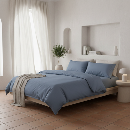 Fundas de edredón EcoPercal azul marino de Morfeo vestidas en cama de dormitorio mediterráneo luminoso.