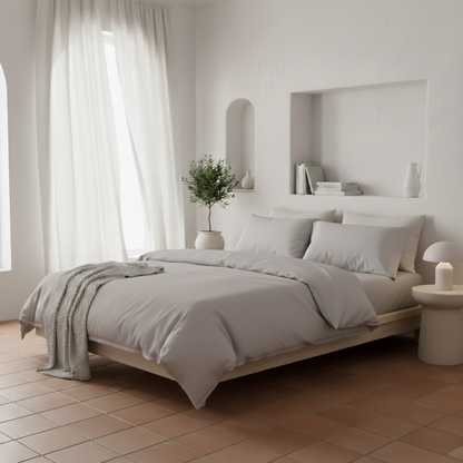 Fundas de edredón EcoPercal gris de Morfeo vestidas en cama de dormitorio mediterráneo luminoso.