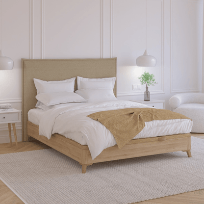 Mantita espiga de Morfeo a los pies de una cama con ropa blanca y cabecero tapizado en dormitorio claro.