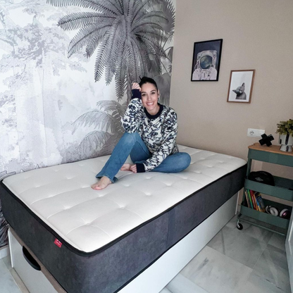 Mujer sentada sobre el colchón Altus de Morfeo en dormitorio luminoso.