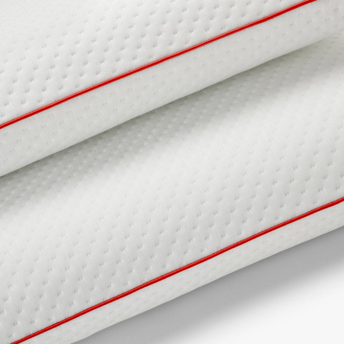 Primer plano del tejido de la funda con ribete rojo de la almohada viscoelástica SojaVisco de Morfeo.