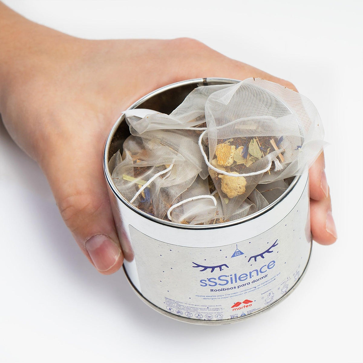 Lata abierta de Rooibos relajante para dormir de Morfeo sostenida con las manos, llena de bolsitas de infusión.