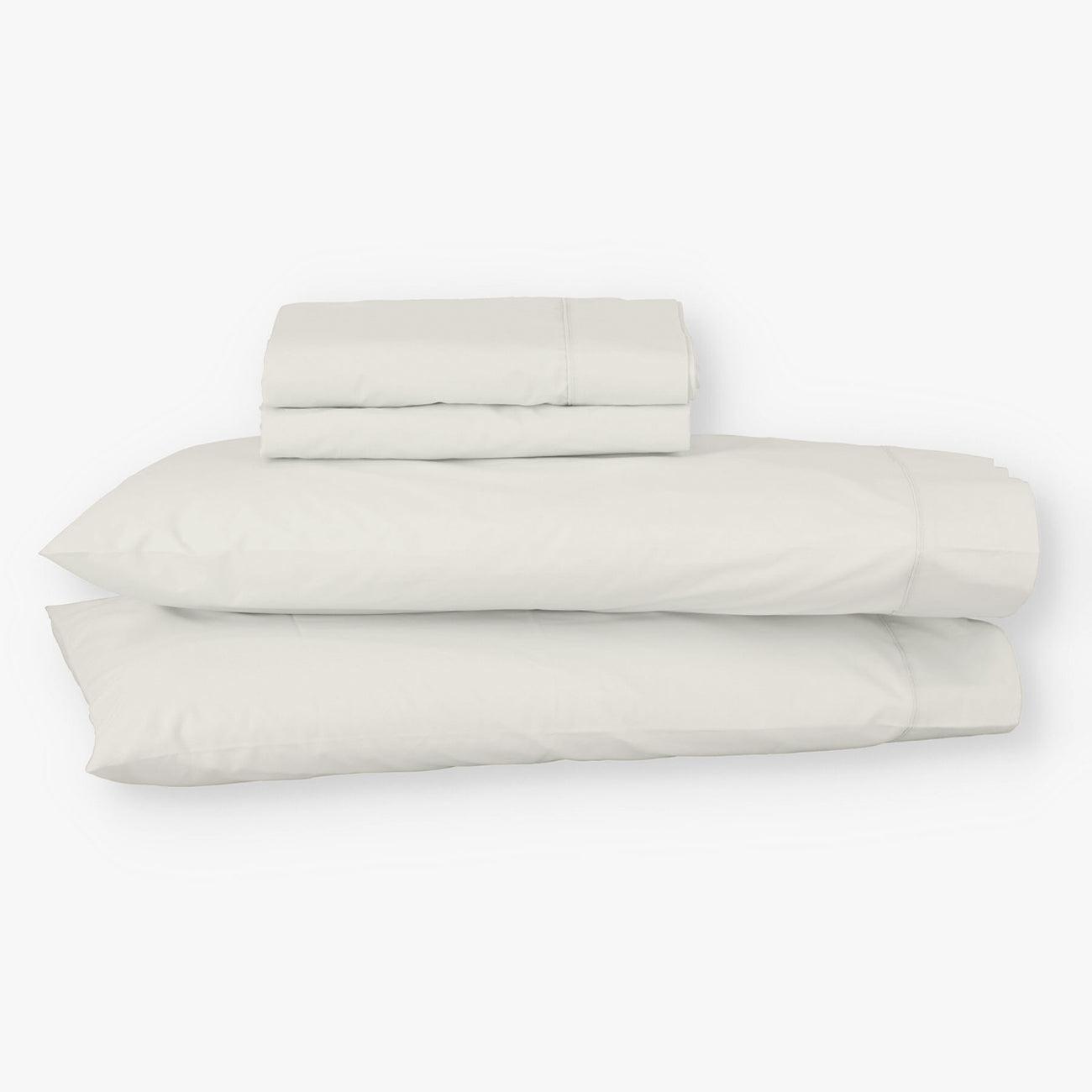Juego de sábanas de algodón percal beige de Morfeo con fundas colocadas en almohadas visibles.