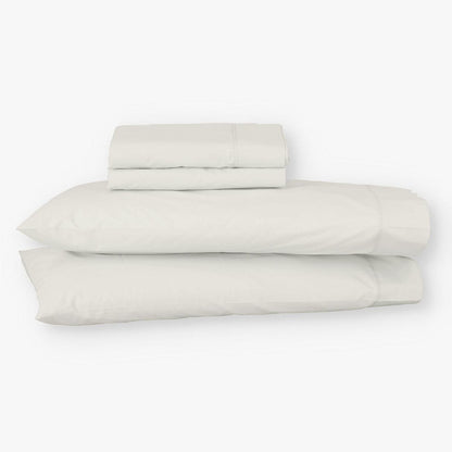 Juego de sábanas de algodón percal beige de Morfeo con fundas colocadas en almohadas visibles.
