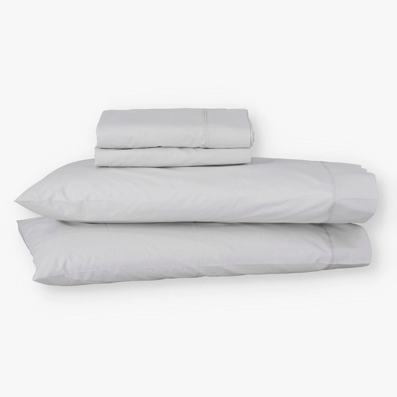 Juego de sábanas de algodón percal gris de Morfeo con fundas colocadas en almohadas visibles.