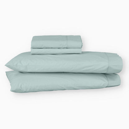 Juego de sábanas de algodón percal verde de Morfeo con fundas colocadas en almohadas visibles.